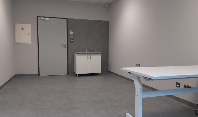 Na lewo od drzwi jest obudowa z klapą do sterowania elektroniką. Po prawej stronie od drzwi stoi szafka z drzwiczkami, na której jest zamontowany zlew z kranem